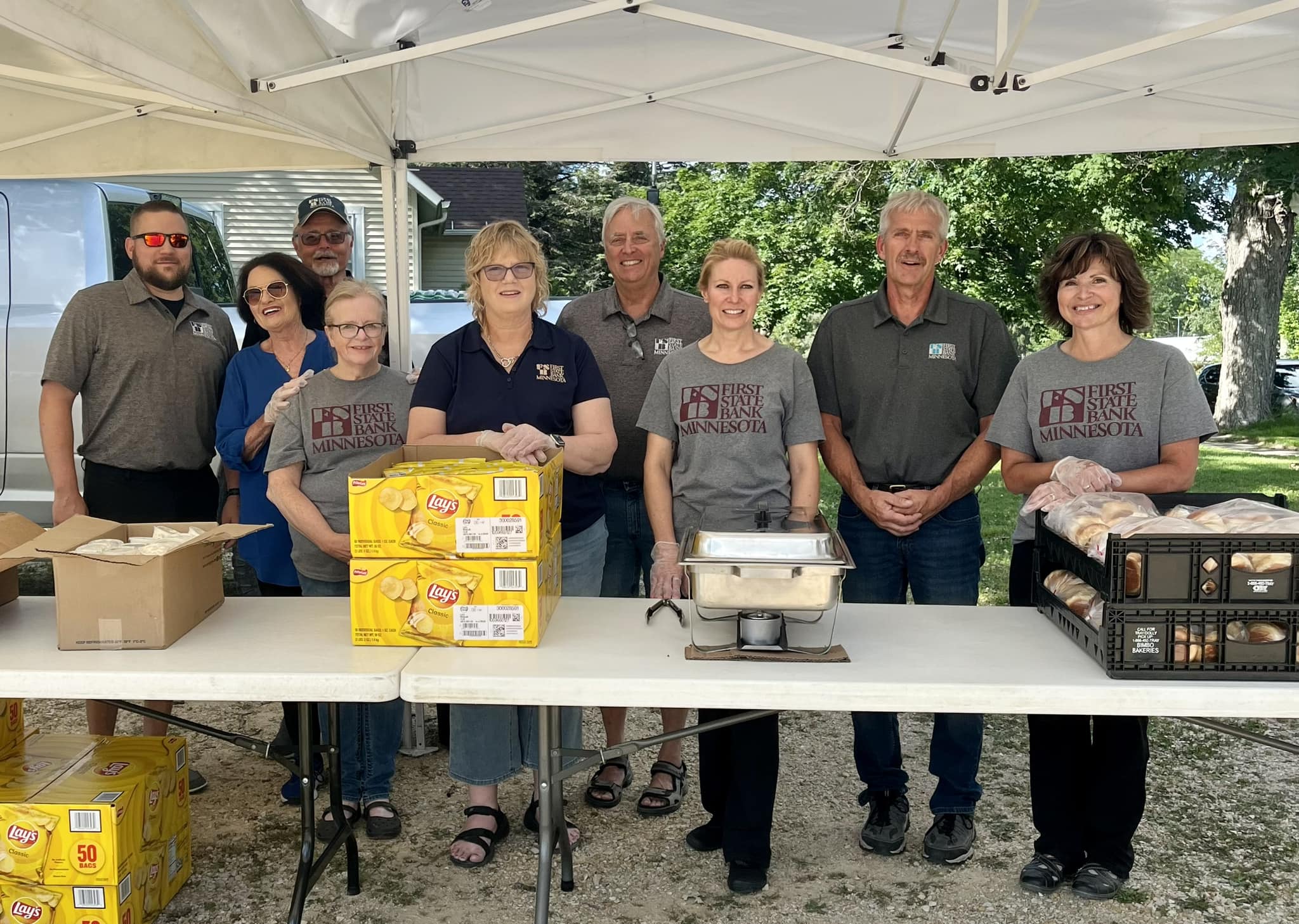 A group of people standing behind a table ready to hand out food.