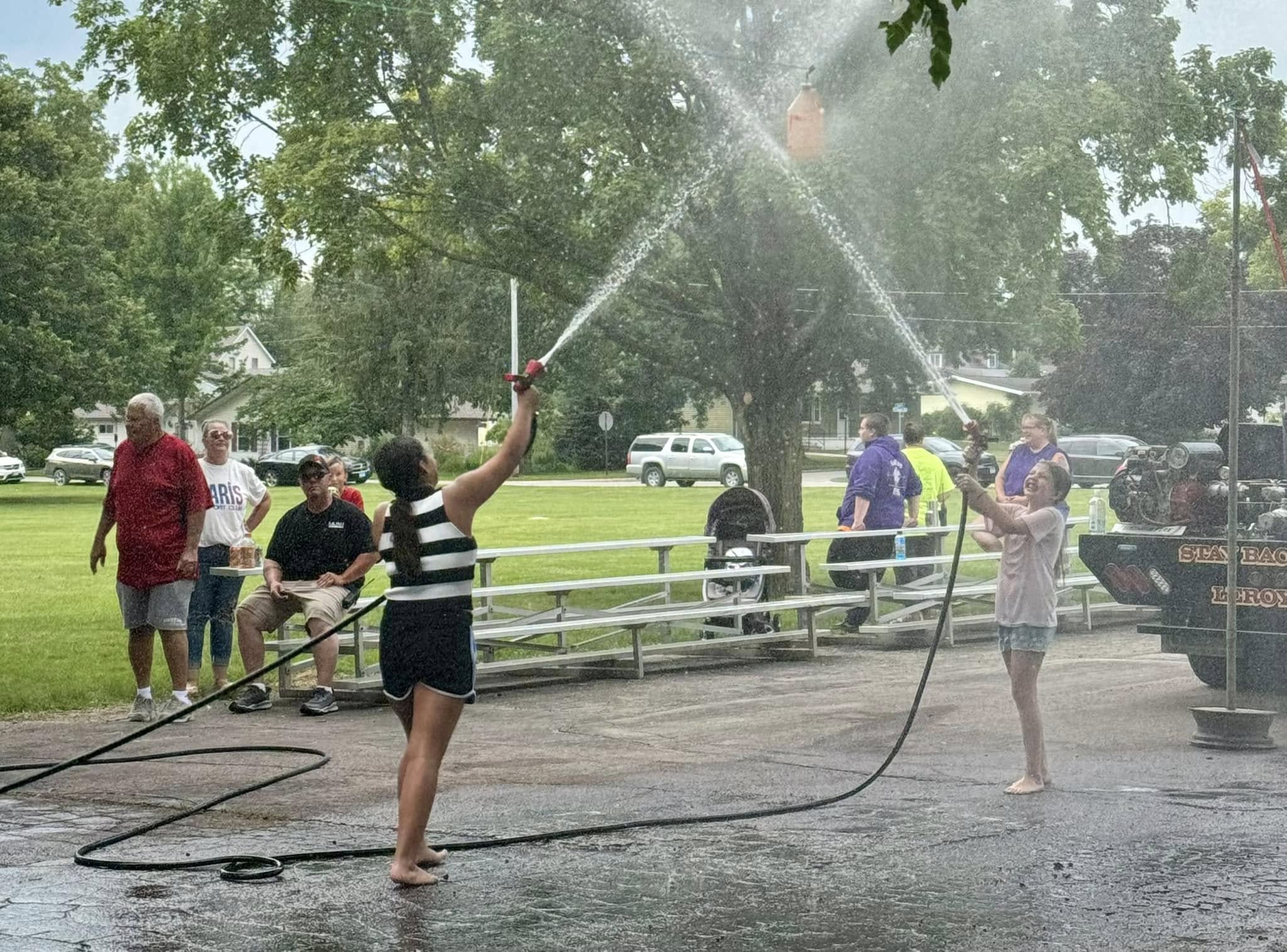 Two kids aiming water hoses at a moving goal.