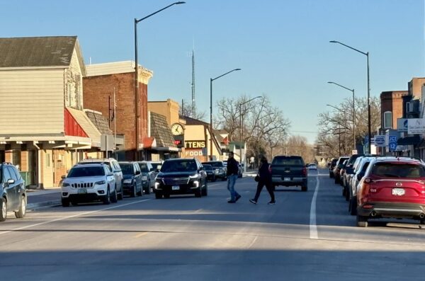 Main Street with parked cars and people crossing the street